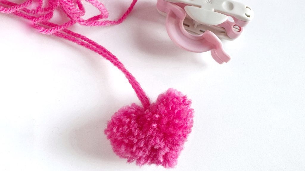 Pompom in de vorm van een hart, met een pompommaker ernaast