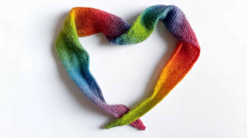 Een Sophie scarf in regenboogkleuren, neergelegd in de vorm van een hart
