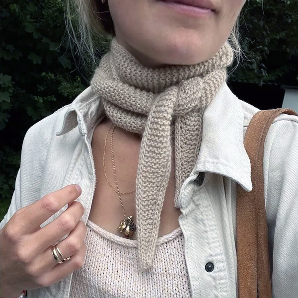 Een close-up van een vrouw die een zandkleurige Sophie scarf draagt